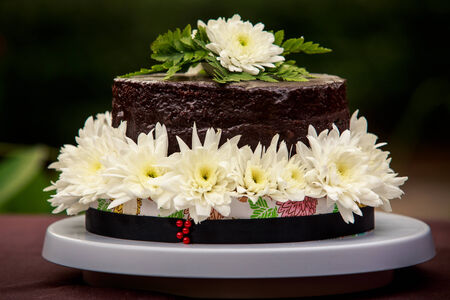 chocolate delicious cake decorated with white flowers and green leafsの写真素材