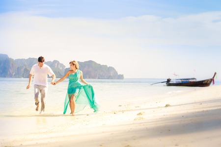 young handsome man run with beautiful blonde girlfriend in blue dressの写真素材