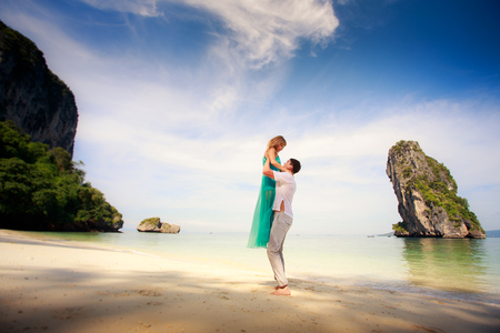 young handsome man hold up his beautiful blonde girlfriend in blue dressの写真素材