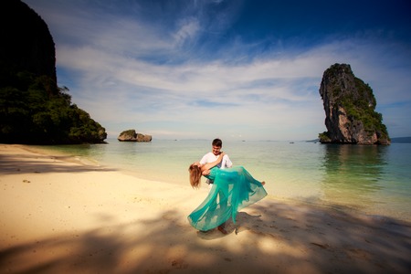 young handsome man hold on arms his beautiful blonde girlfriend in blue dressの写真素材
