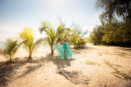 beautiful blonde woman pose in elegant dress in green palm leafsの写真素材