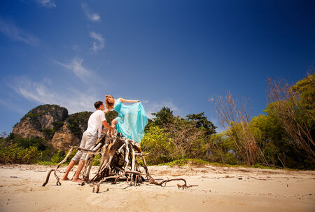 handsome man look at beautiful blonde woman in blue dress among green treesの写真素材