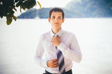 young handsome groom wear grey tie on white shirt on island in Thailandの写真素材