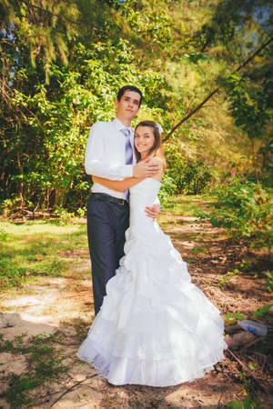 young brunette bride and handsome groom embrace in green jungleの写真素材
