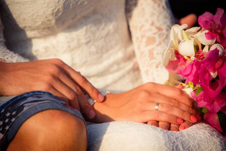 hands of bride and  groom with pink bouquetの写真素材