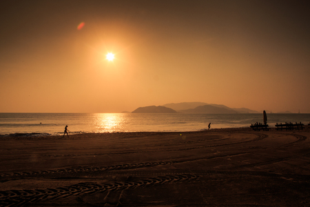 panorama of sun path at sunrise above sea and mountains with running on sand beach wavesの写真素材