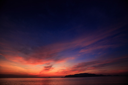 panorama of wave surf against fantastic beautiful dark blue and red sky with fleecy clouds before sunriseの写真素材