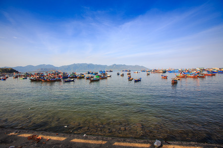 large group of Vietnamese colourful fishing boats in azure sea with transparent shallow water on foregroundの写真素材