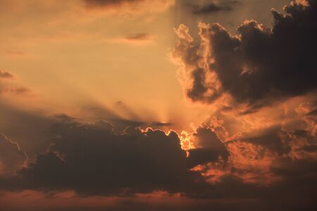 panorama of rising sunbeams from behind golden cumulus cloudsの写真素材