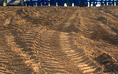 closeup fresh tracks of tractors on wet spring ground car wheels at background