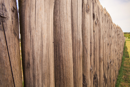 closeup high old wooden fence of logs in form of palisade vanish into space in countrylandの写真素材