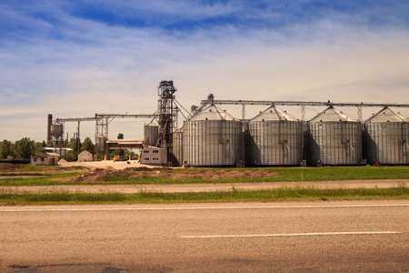 panorama of production yard and metal tank of modern silo in countryside near lake by roadの写真素材