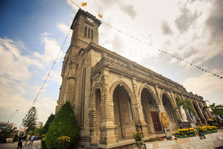 large old Catholic cathedral with tower decorated with flags in Vietnamの写真素材