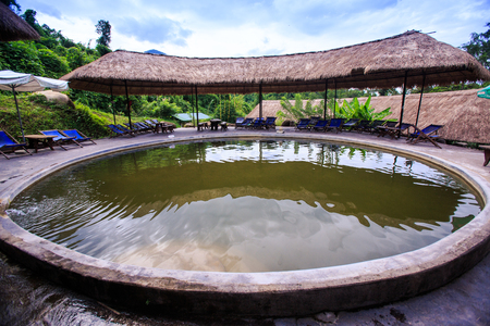 closeup round hot water pool to bathe against plants folding chairs reed umbrellas in tropical park in Vietnamのeditorial素材