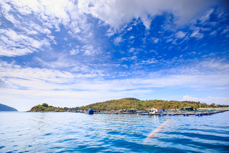 panorama of azure sea green hill island against blue sky with big white cloudsの写真素材