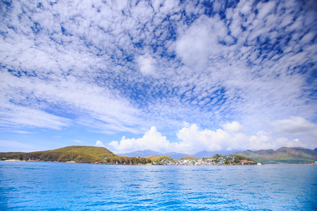 clouds lace in blue sky above azure sea distant hills and resort cityの写真素材