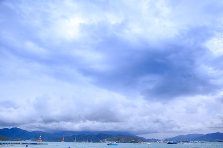 tourist ship on azure sea against distant resort city mountains blue sky white cloudsの写真素材