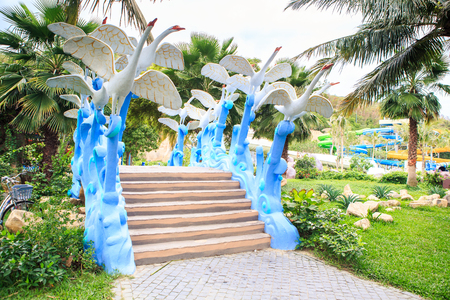 stone steps original barriers with swan sculptures against palms in tropical parkの写真素材