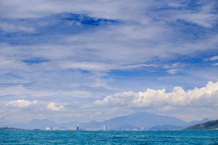 panorama of resort city against distant mountain and azure sea boats blue sky with white big cloudsの写真素材