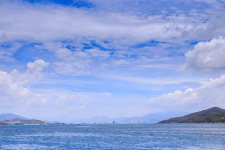 panorama of clouds lace in blue sky above azure sea green hill and distant resort cityの写真素材