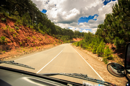 bright sunny road among wooded hills out of the windowの写真素材