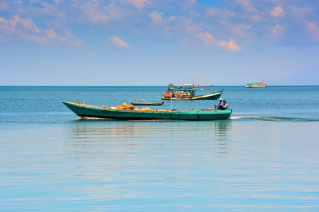 Vietnamese fishing boats in tranquil sea up to horizon against sky at sunriseの写真素材