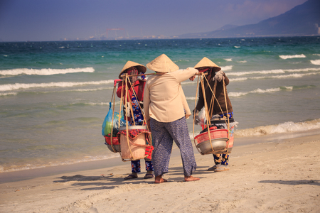NHA TRANG / VIETNAM - APRIL 16 2016: Local sellers in Vietnamese hats with goods in baskets on yoke on April 16 in Nha Trangのeditorial素材