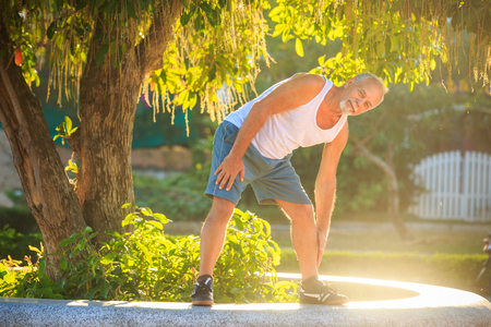 bearded gray man in vest shorts does morning exercises bendsの写真素材