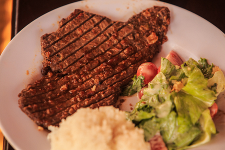 closeup kangaroo steak cooked on grill with vegetables rice on white plate on black backgroundの写真素材