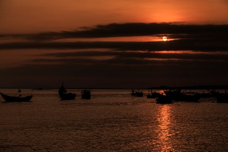 fantastic view fishing boat silhouettes melt into the background in the ocean bay at late dark sunsetの写真素材