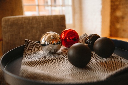 Christmas balls are on a tray against the window