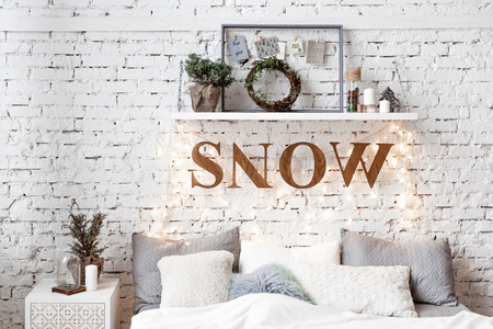 A spacious white light bedroom in a loft style with a decorated Christmas tree and a garland.の写真素材