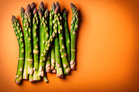 Bunch of fresh green asparagus on orange background, top view, AI Generatedの素材