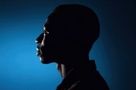 side view profile outline of african american male silhouette against deep blue backgroundの素材