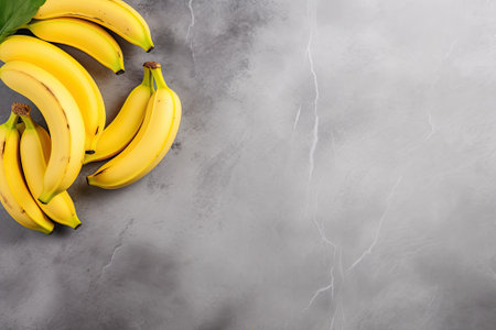 Two bright yellow bananas are placed on a gray surface, creating a minimalist flat lay. These bananaの素材