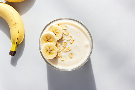 A photograph showcasing a glass of banana oats smoothie or vanilla milkshake placed on a vibrant marの素材