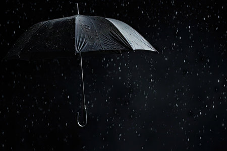 Rain drops falling from a black umbrella for unfavorable weather or safety in winterの素材