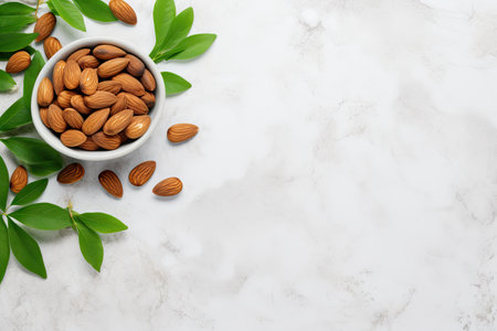 Delicious almonds and fresh leaves on white table Flat lay with space for textの素材