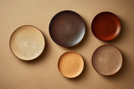 Textured grainy pattern on five plates of varying sizes on beige background Top view of brown and naの素材