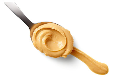 Smooth peanut butter on a spoon against a white backgroundの素材