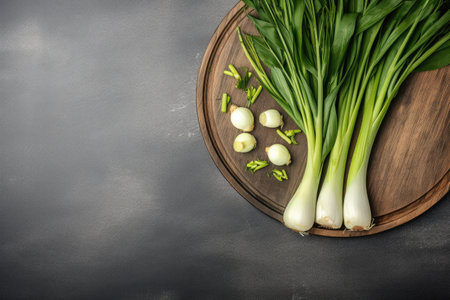 Freshly harvested leeks sliced on a wooden chopping board with a stone background Top view copy spacの素材