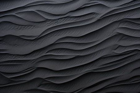 Macro photography of black sand dunes on a beach capturing the texture and wave pattern of the blackの素材