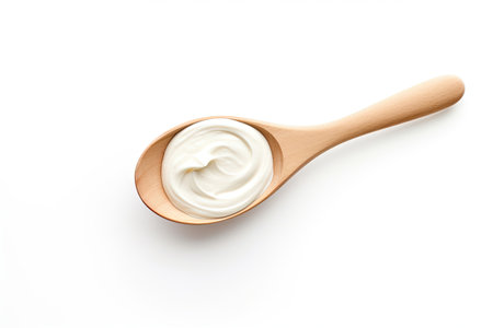Top view of sour cream in a wooden spoon placed on a white backgroundの素材