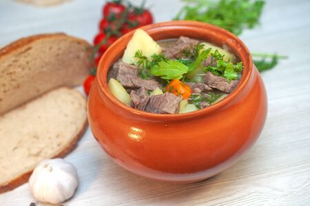 Roast in a pot with beef meat and potatoes on the tableの写真素材