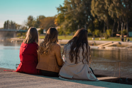 Girls are Talking and Chilling on the River Bank in Beautiful Weatherの写真素材