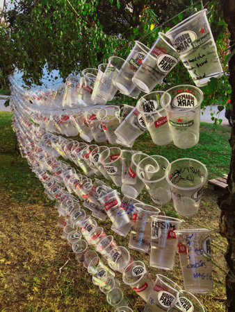 Creative wall made from plastic beer cups, trees background