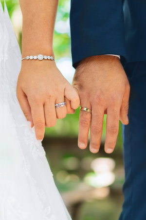 Bride and groom with wedding rings, little fingers locked togetherの写真素材