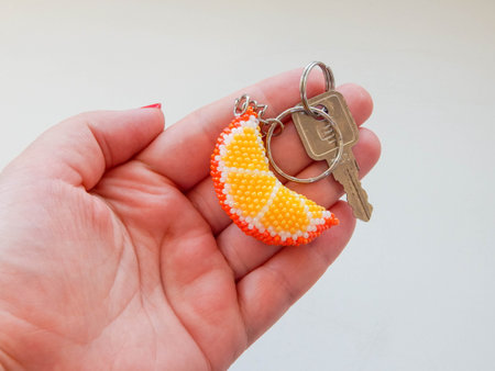 Fruit keychain lies on a woman's palm. Orange keychain in women's hand