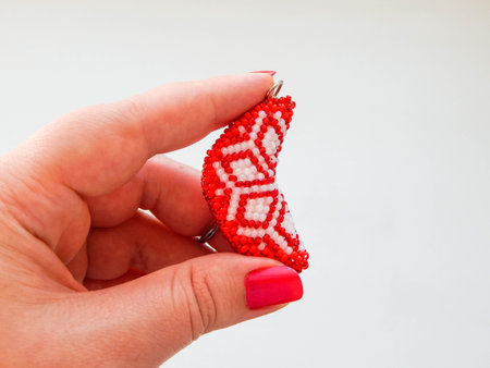 Red keychain in a female hand. Bead colorful key chain in a female hand