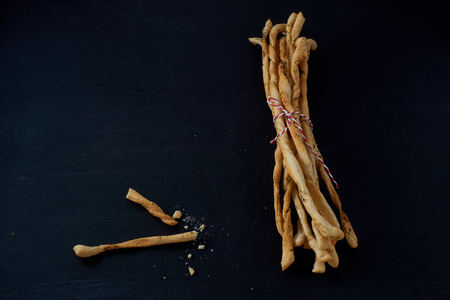 Traditional Italian snack, bread - grissini. On a dark stone table, top view, background with free...